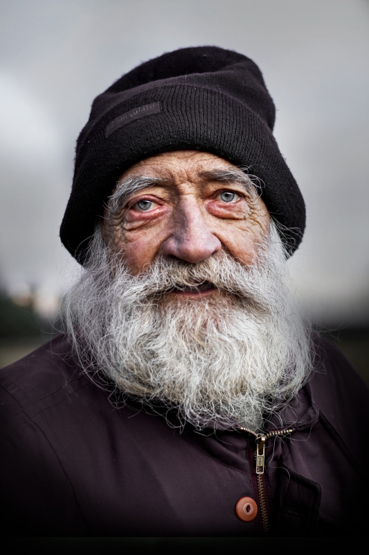 Starý trošku zanedbaný pán. Neudržované vlasy a vousy. Stará čepice a bunda. Oči a vrásčitý obličej vyprávějí příběh dlouhého a nelehkého života.