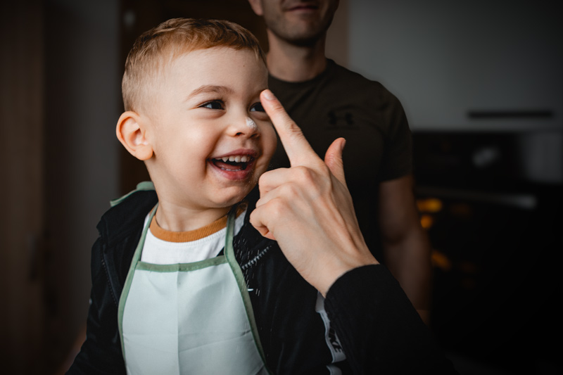 Maminka s dvouletým chlapečkem rozklepávají vajíčko do těsta na buchtu. Domácí vaření. Láska k dítěti. spolupráce.
