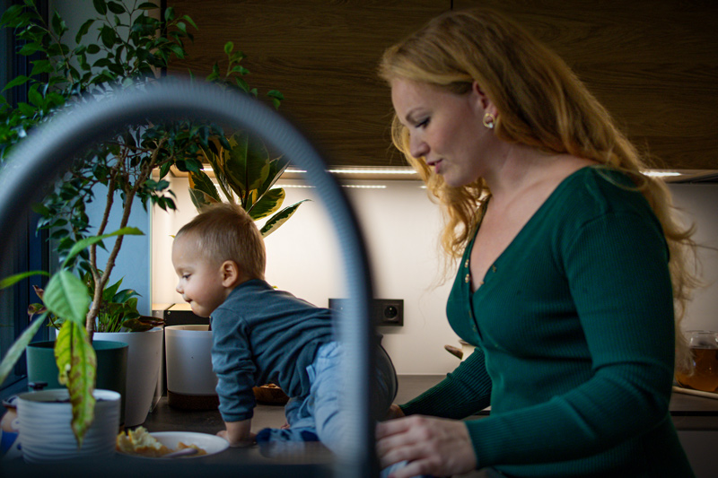 Maminka hlídá roční miminko na kuchyňské lince. Chlapeček zkoumá věci na kuchyňské lince.